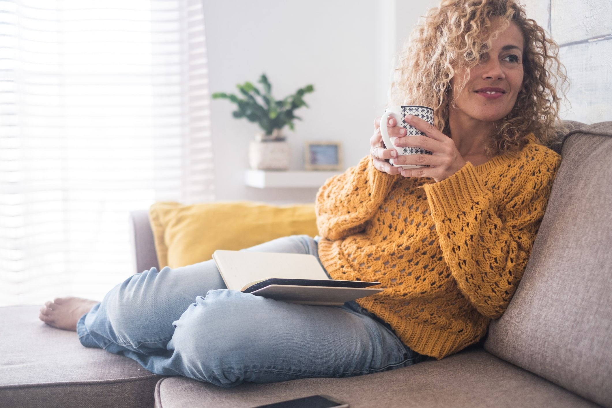 Woman holding a mug and book on her lap